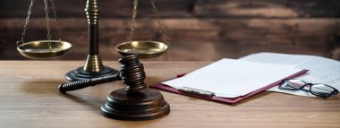 Ahşap masa arkasında hukuk ve adalet sembolleri..