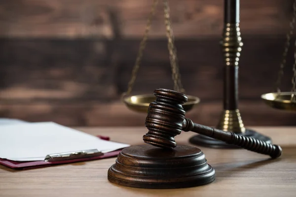 Ahşap masa arkasında hukuk ve adalet sembolleri..