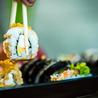 Taze Japon suşi böreği yiyen kişi, popüler Asya yemekleri..