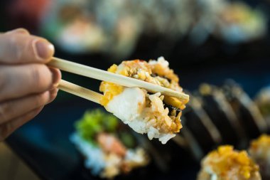 Taze Japon suşi böreği yiyen kişi, popüler Asya yemekleri..