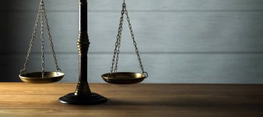 Hukuk ve Adalet 'in hayatı hâlâ devam ediyor. Ahşap masa arkasında pullar var..