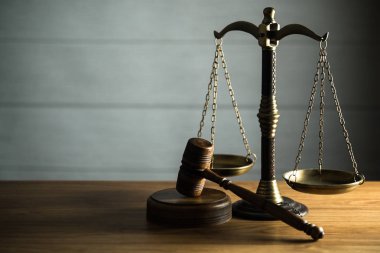 Ahşap masa arkasında hukuk ve adalet sembolleri..