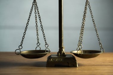 Hukuk ve Adalet 'in hayatı hâlâ devam ediyor. Ahşap masa arkasında pullar var..