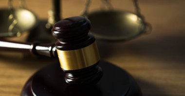 Ahşap masa arkasında hukuk ve adalet sembolleri..