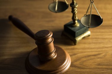 Ahşap masa arkasında hukuk ve adalet sembolleri..