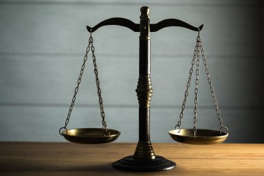 Hukuk ve Adalet 'in hayatı hâlâ devam ediyor. Ahşap masa arkasında pullar var..