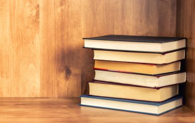 Ahşap rafta kapalı kitap yığını.