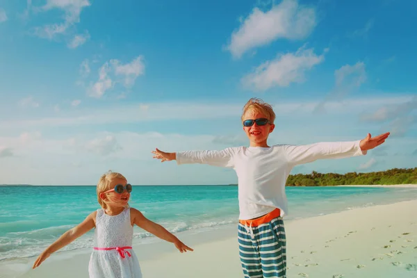 Szczęśliwy mały chłopiec i dziewczyna grać na tropikalnej plaży — Zdjęcie stockowe