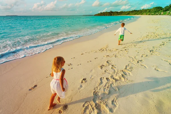 Malý chlapec a dívka běží na pláži — Stock fotografie