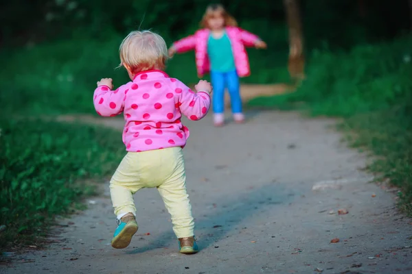 Primeros pasos de la niña con la hermana al aire libre — Foto de Stock