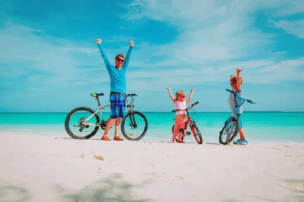Felice padre con i bambini in bicicletta sulla spiaggia — Foto Stock