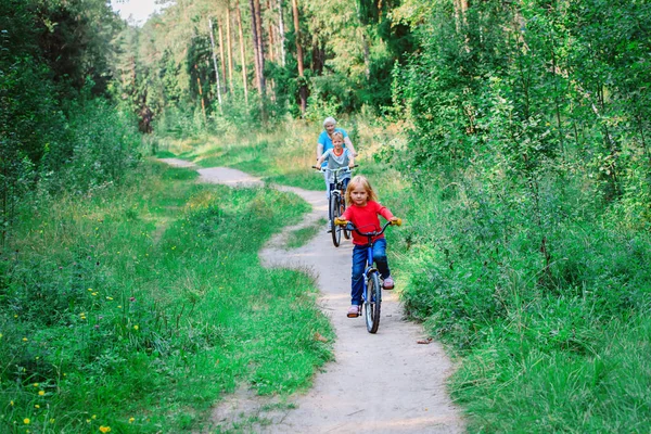 Avó sênior ativo com crianças andar de bicicleta na natureza — Fotografia de Stock