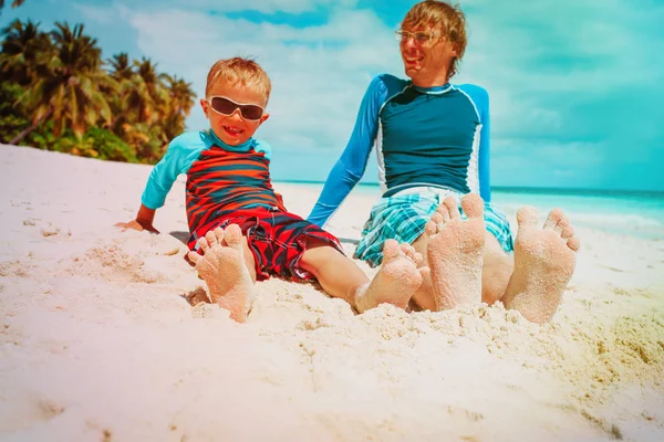 father and son relax feet on summer beach