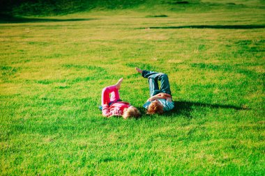 Küçük oğlan ve kız yeşil çimlerde rahatlar.