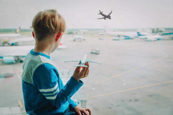 Chico jugando con juguete avión mientras espera en aeropuerto — Foto de Stock