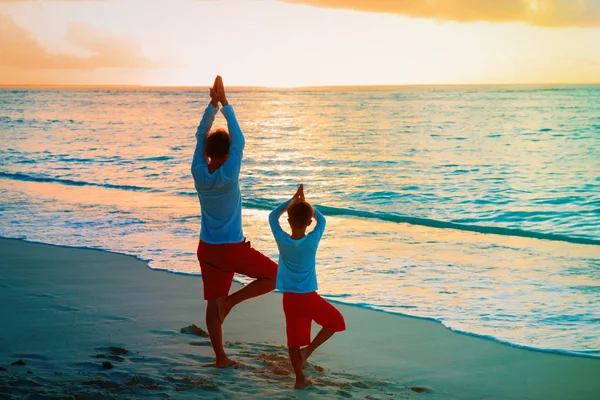 Pai e filho fazendo ioga na praia do pôr do sol — Fotografia de Stock