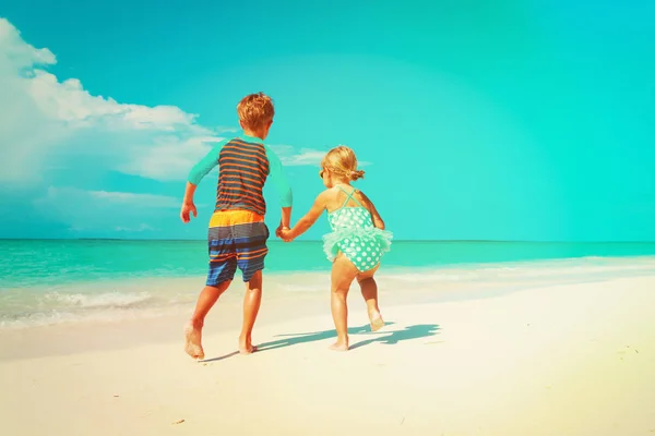 Küçük kız ve erkek çalıştırmak sahilde su ile oynamak — Stok fotoğraf