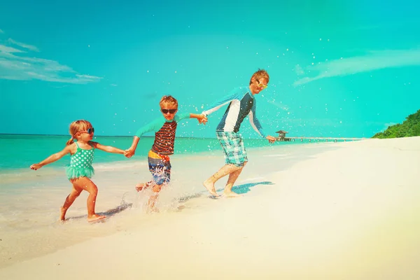 Gelukkig gezin - vader met kinderen spelen met water lopen op strand — Stockfoto