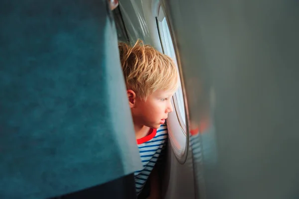 Niño viajando en avión mirando por la ventana — Foto de Stock