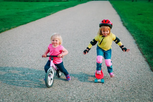 Carino ragazze felici in bicicletta e skateboard giro — Foto Stock