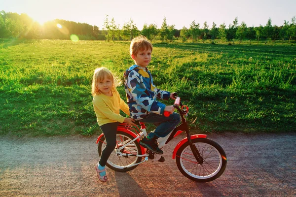 Ragazzo e ragazza in sella alla bicicletta in natura tramonto — Foto Stock