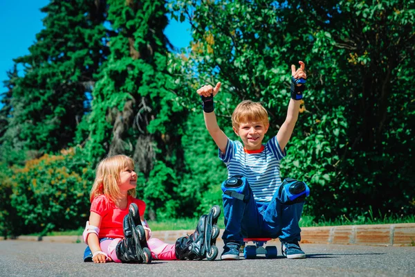 Bambini felici sui pattini a rotelle e skateboard fuori — Foto Stock