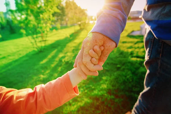 Vader en dochter hand in hand bij zonsondergang, ouderschap — Stockfoto