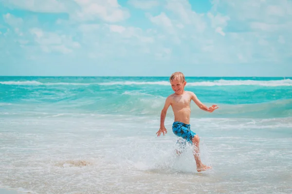 Gelukkig weinig jongen lopen spelen met water genieten van strand — Stockfoto