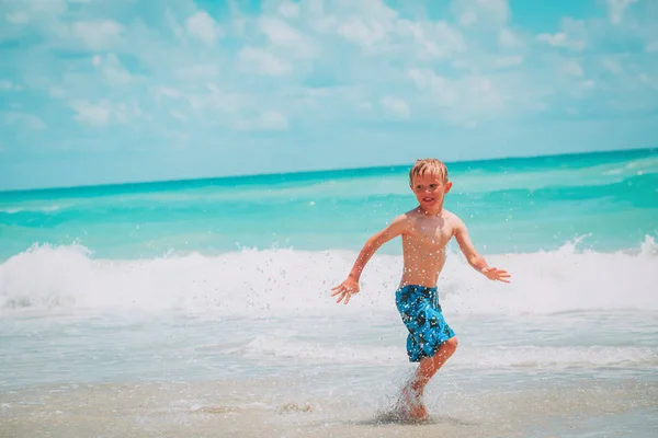 Gelukkig weinig jongen lopen spelen met water genieten van strand — Stockfoto