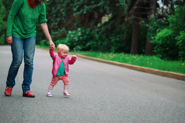 Första steg av liten flicka med mamma utomhus — Stockfoto