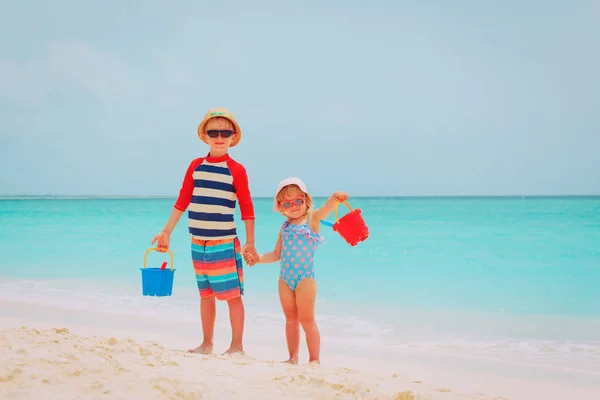 Szczęśliwy mały chłopiec i dziewczyna grać z piasku na plaży — Zdjęcie stockowe