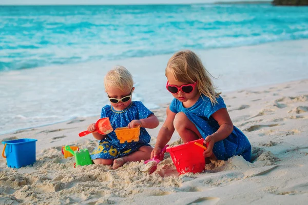 Little girls play with sand on beach — Stock Photo, Image