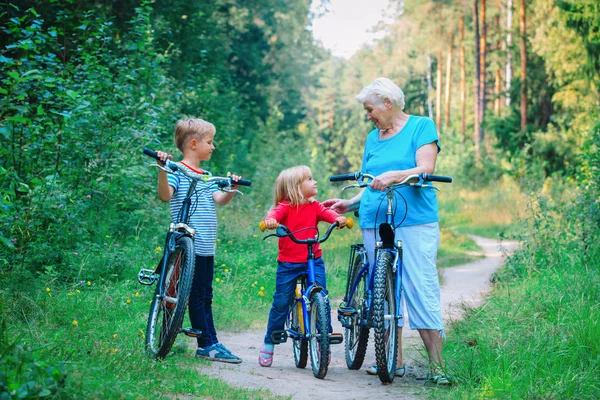 Avó feliz com crianças andando de bicicleta na natureza — Fotografia de Stock