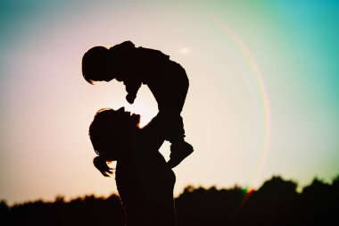 Anne ve küçük bebek günbatımında oynamak