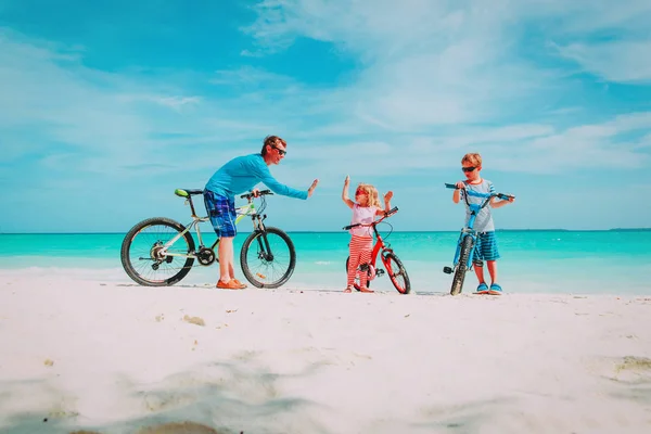 Felice padre di famiglia con figlio e figlia- in bicicletta sulla spiaggia — Foto Stock