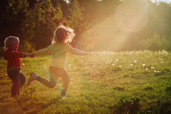 Щасливі діти біжать грати в природі заходу сонця — стокове фото