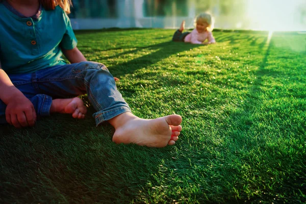 Musim panas di kota-anak bermain kaki telanjang di rumput di latar belakang perkotaan — Stok Foto