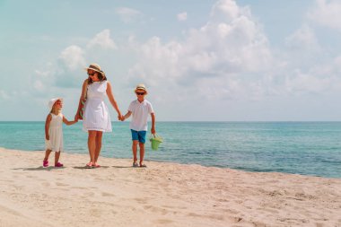 Anne ve oğlu ve kızı sahilde yürüyor.