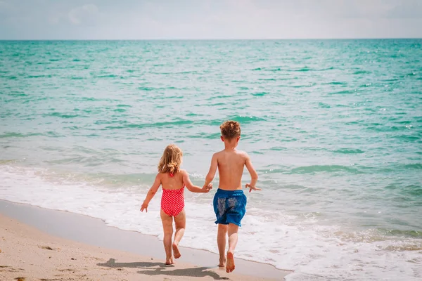 Маленький мальчик и девочка бегают играть на пляже — стоковое фото