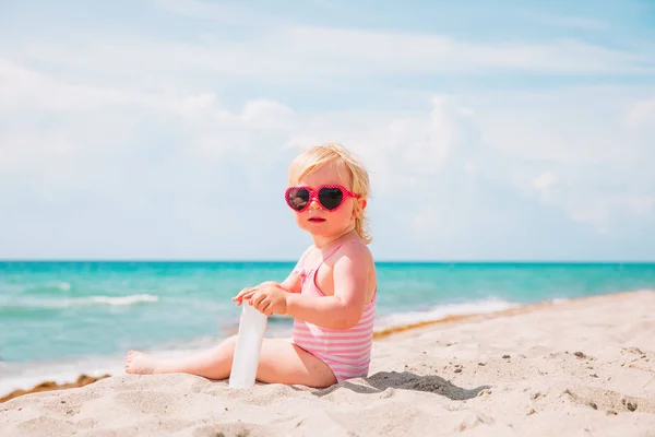 Schattig klein meisje met sunblock crème op tropisch strand — Stockfoto