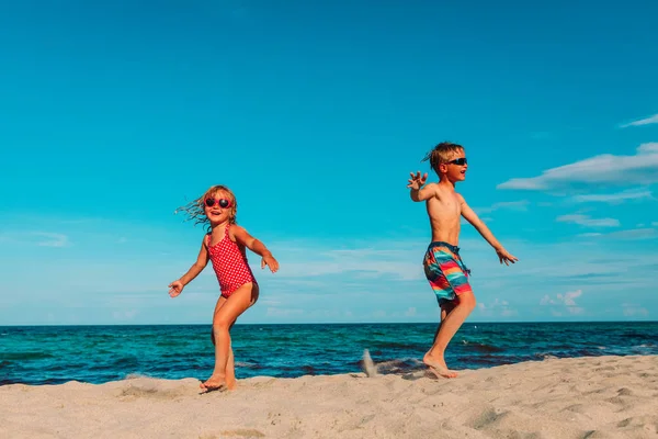 Malý chlapec a dívka hrát tanec na pláži — Stock fotografie