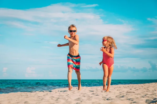 Niño y niña corriendo en la playa — Foto de Stock