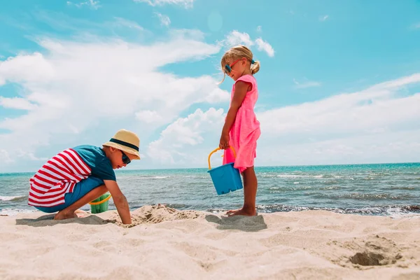 Malý chlapec a dívka hrát s pískem na pláži — Stock fotografie