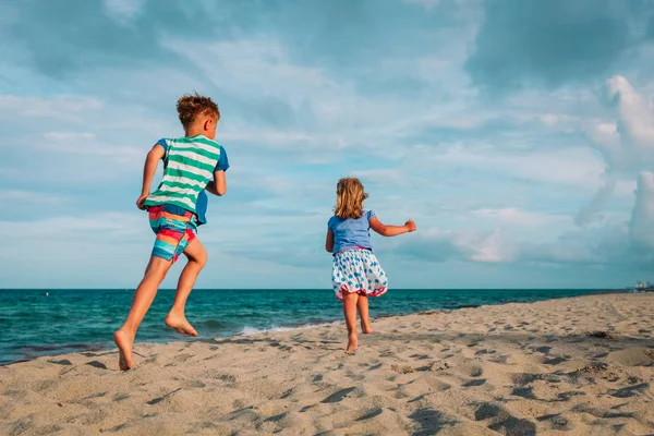 Niño y niña corriendo en la playa — Foto de Stock