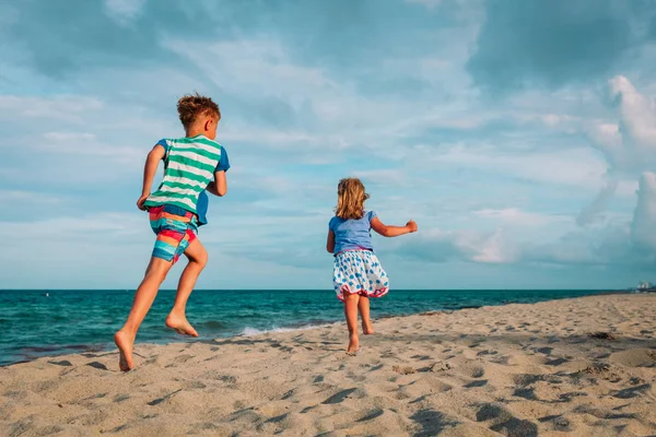 Menino e menina correndo na praia — Fotografia de Stock