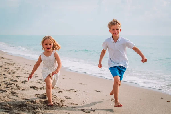 Счастливые мальчик и девочка бегают играть на пляже — стоковое фото