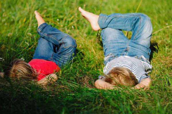 Anak kecil dan anak perempuan bersantai di rumput hijau — Stok Foto