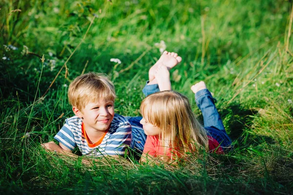 Happy cute anak laki-laki dan gadis bersantai di rumput hijau — Stok Foto