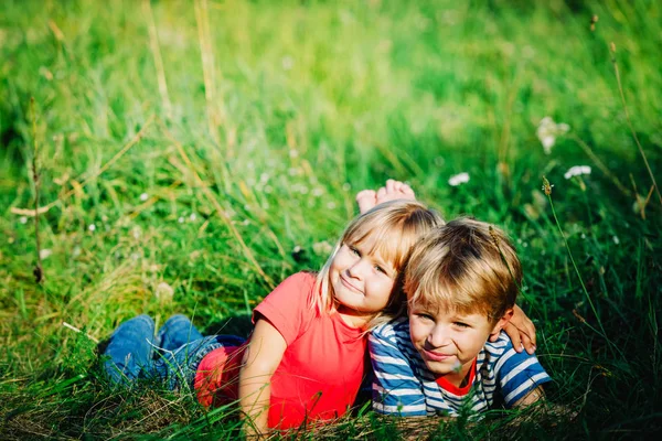 Happy cute anak laki-laki dan gadis bersantai di rumput hijau — Stok Foto