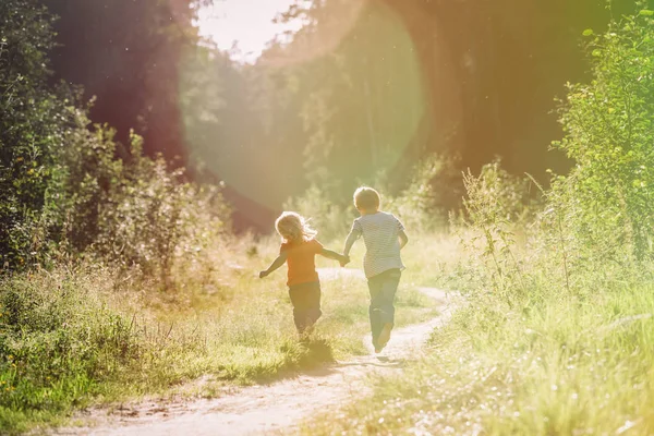 Glückliche kleine Jungen und Mädchen laufen bei Sonnenuntergang Natur — Stockfoto